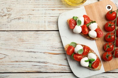 Photo of Delicious sandwiches with mozzarella, fresh tomatoes and basil on white wooden table, flat lay. Space for text