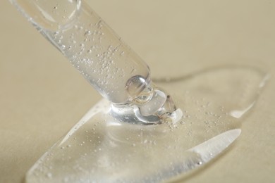 Pipette with cosmetic serum on beige background, closeup