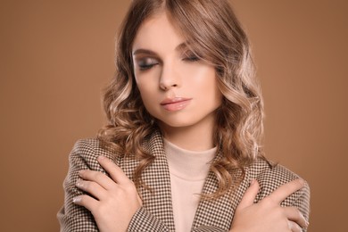 Portrait of young woman with beautiful makeup on light brown background