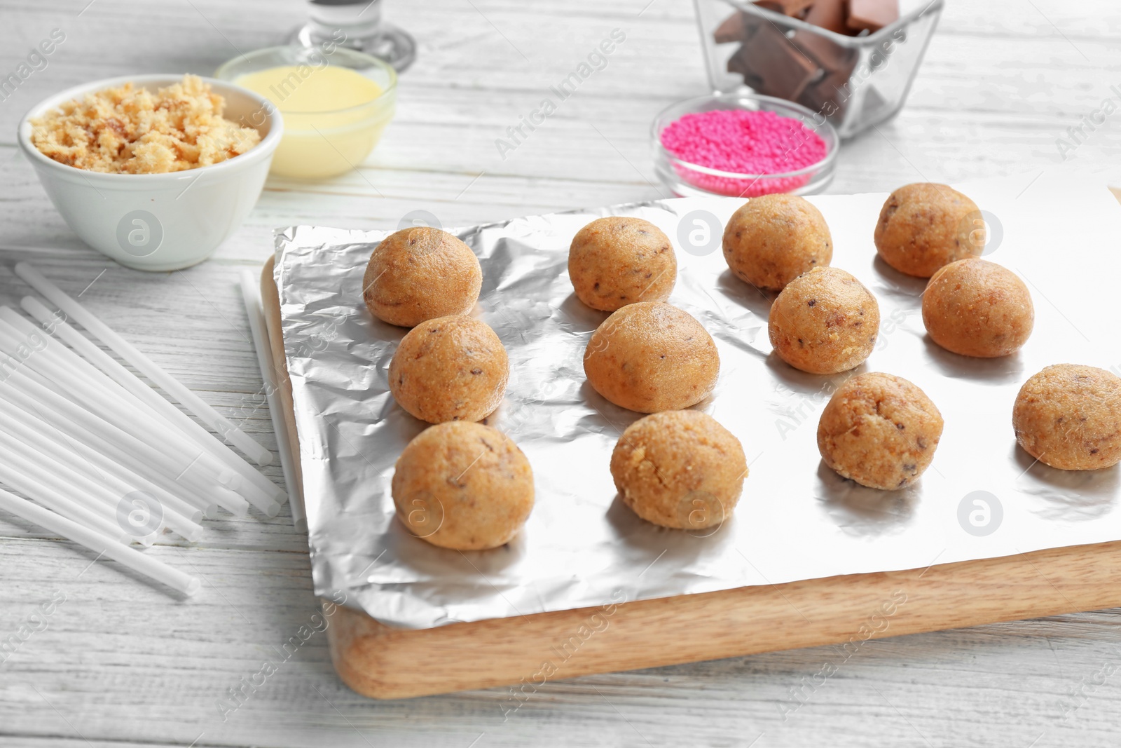 Photo of Board with half made cake pops on white wooden table