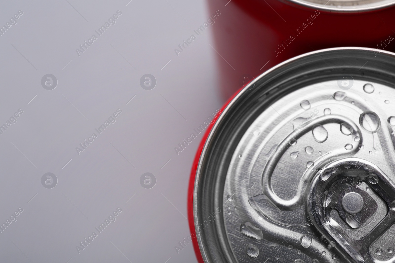 Photo of Energy drinks in wet cans on grey background, top view. Space for text