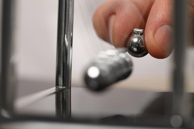Photo of Man playing with Newton's cradle, closeup. Physics law of energy conservation