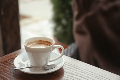 Cup of delicious aromatic coffee on table