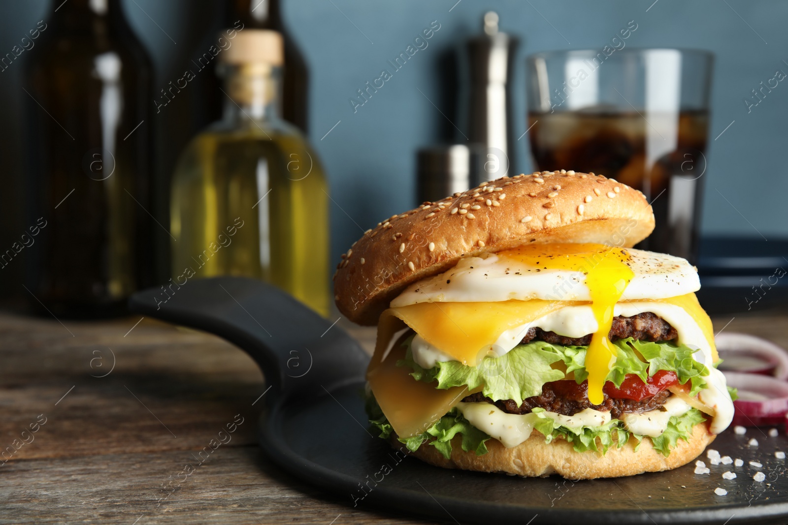 Photo of Tasty burger with fried egg on tray against blurred background, space for text