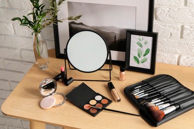 Photo of Mirror, makeup products and pictures on wooden dressing table