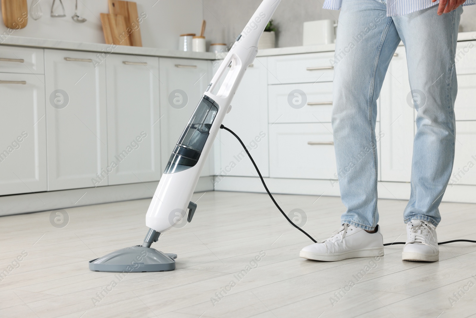 Photo of Man cleaning floor with steam mop at home, closeup