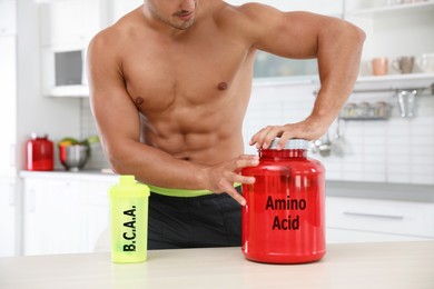 Image of Young athletic man preparing amino acids drink in kitchen