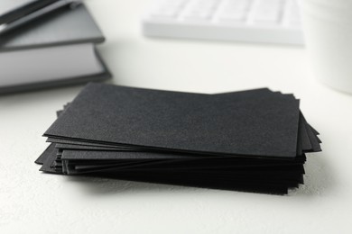 Blank black business cards on white table, closeup. Mockup for design