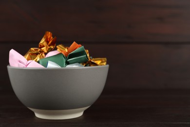 Photo of Candies in colorful wrappers on wooden table. Space for text