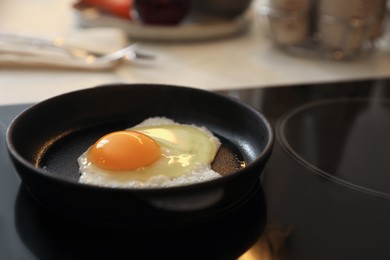 Photo of Frying pan with fresh egg on stove, space for text