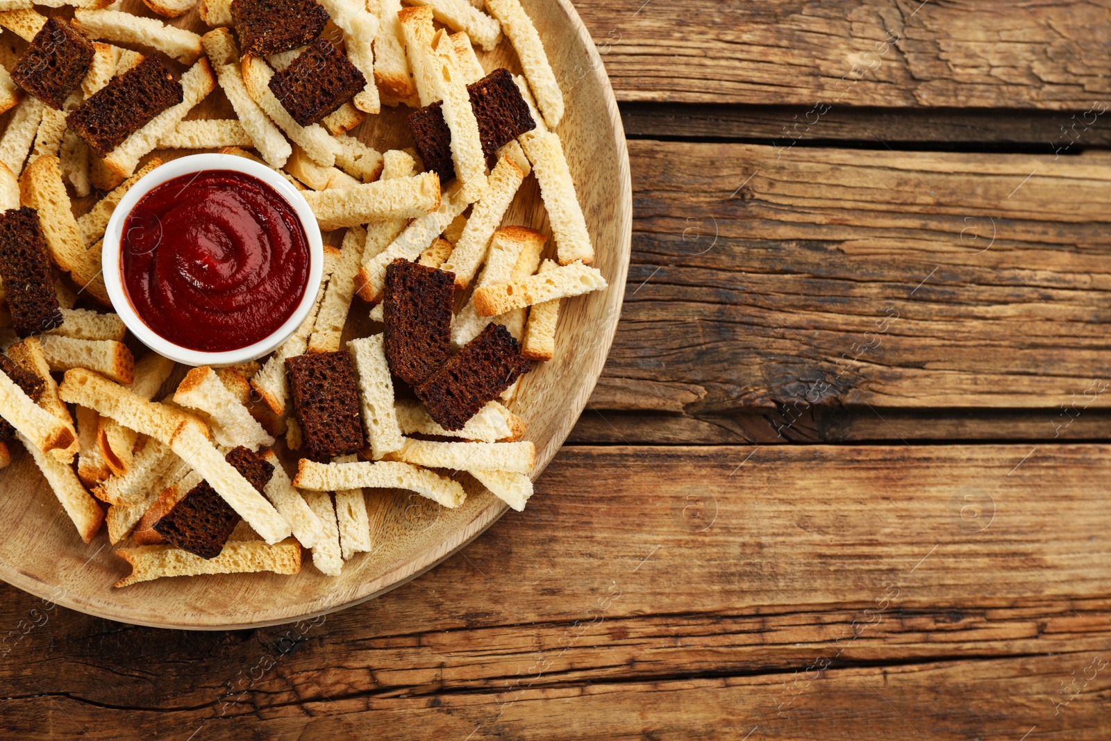 Photo of Delicious hard chucks with ketchup on wooden table, top view. Space for text