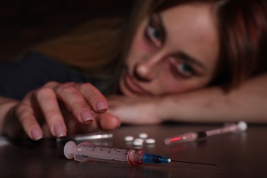 Photo of Addicted woman at table, focus on different drugs