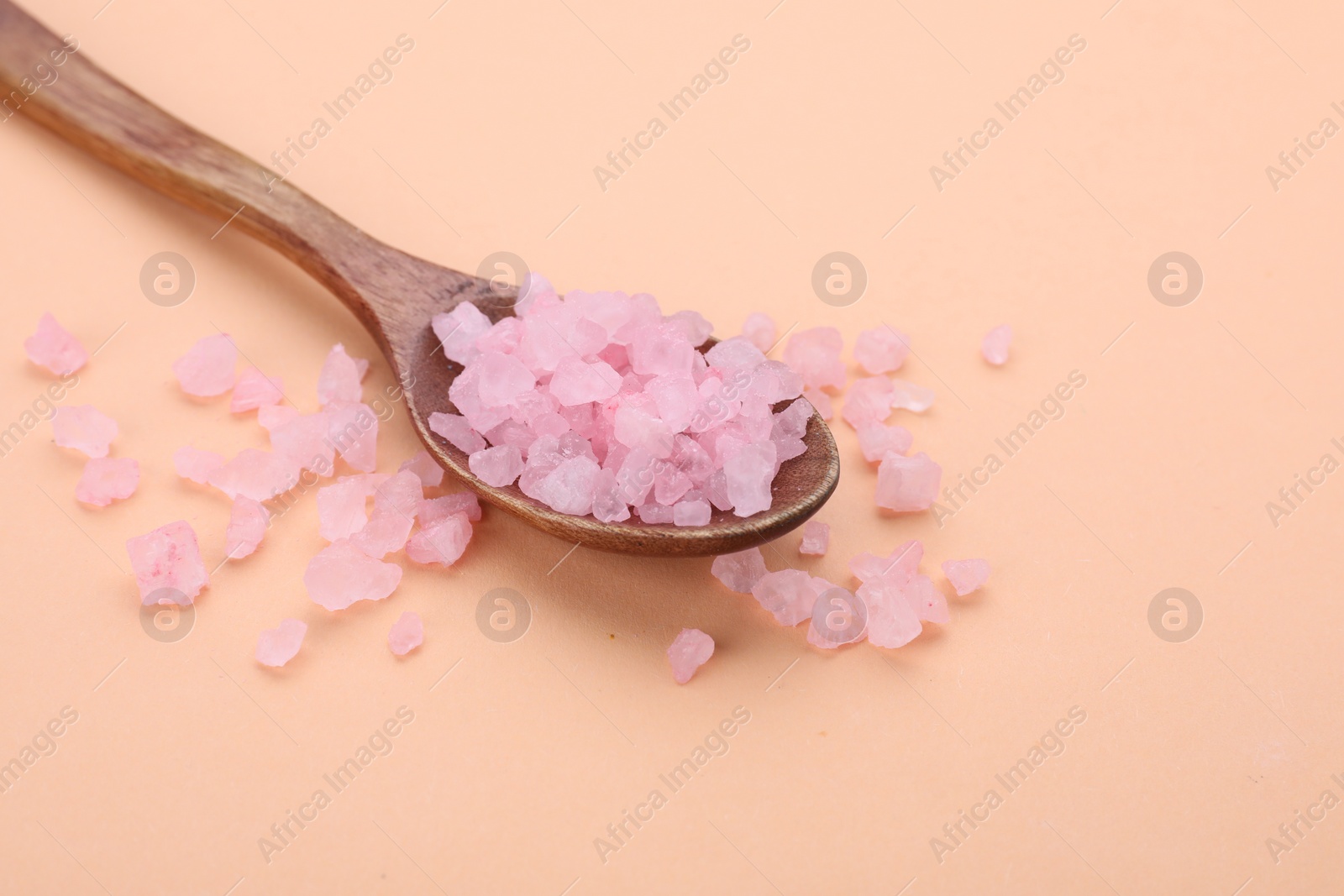 Photo of Spoon with pink sea salt on beige background, space for text