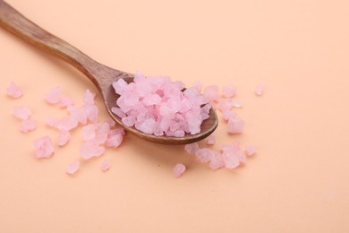 Spoon with pink sea salt on beige background, space for text