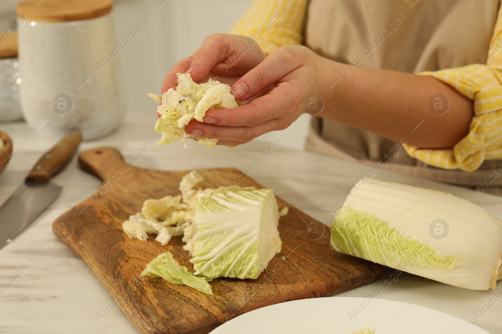 Photo of Woman with cut Chinese cabbage at white kitchen table, closeup