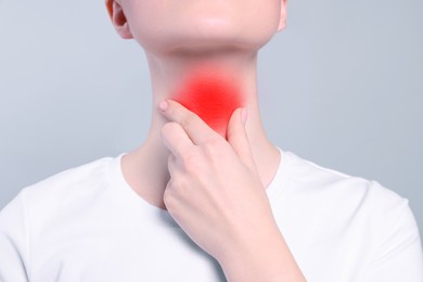 Endocrine system. Woman doing thyroid self examination on grey background, closeup