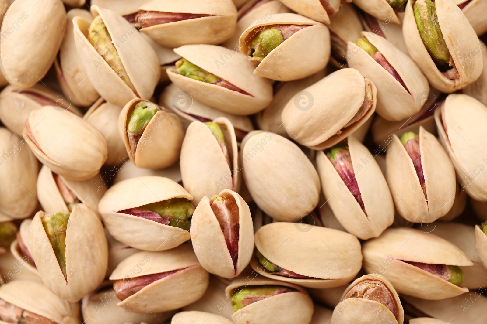 Photo of Tasty unpeeled pistachios as background, top view