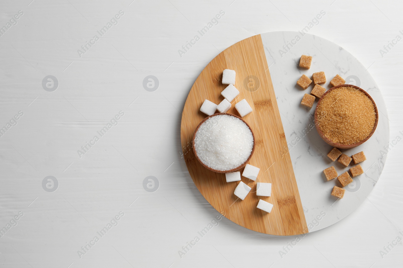 Photo of Different types of sugar on white wooden table, top view. Space for text