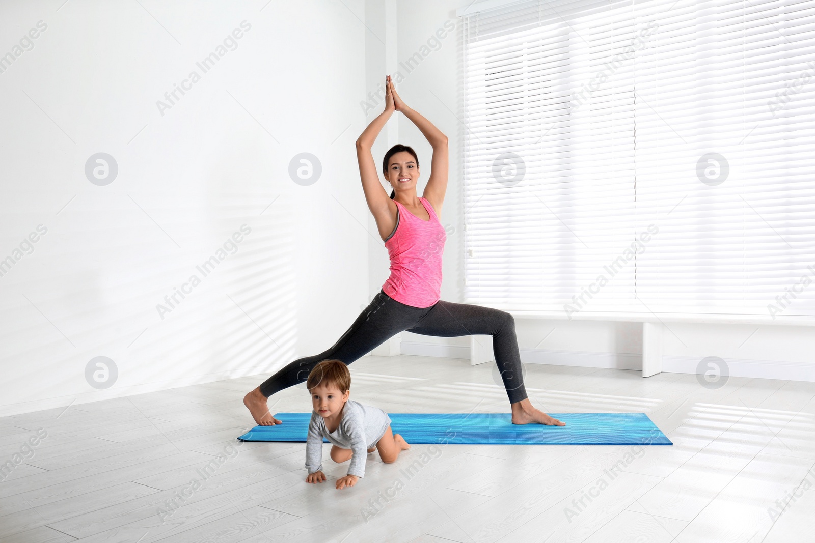 Photo of Young woman doing exercise with her son indoors. Home fitness