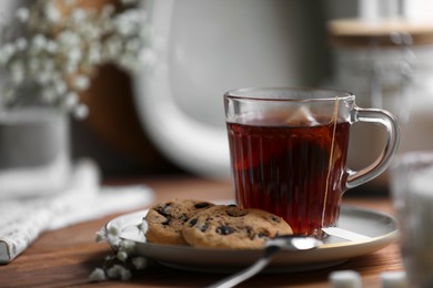 Photo of Cup of freshly brewed tea and delicious cookies on wooden table, space for text