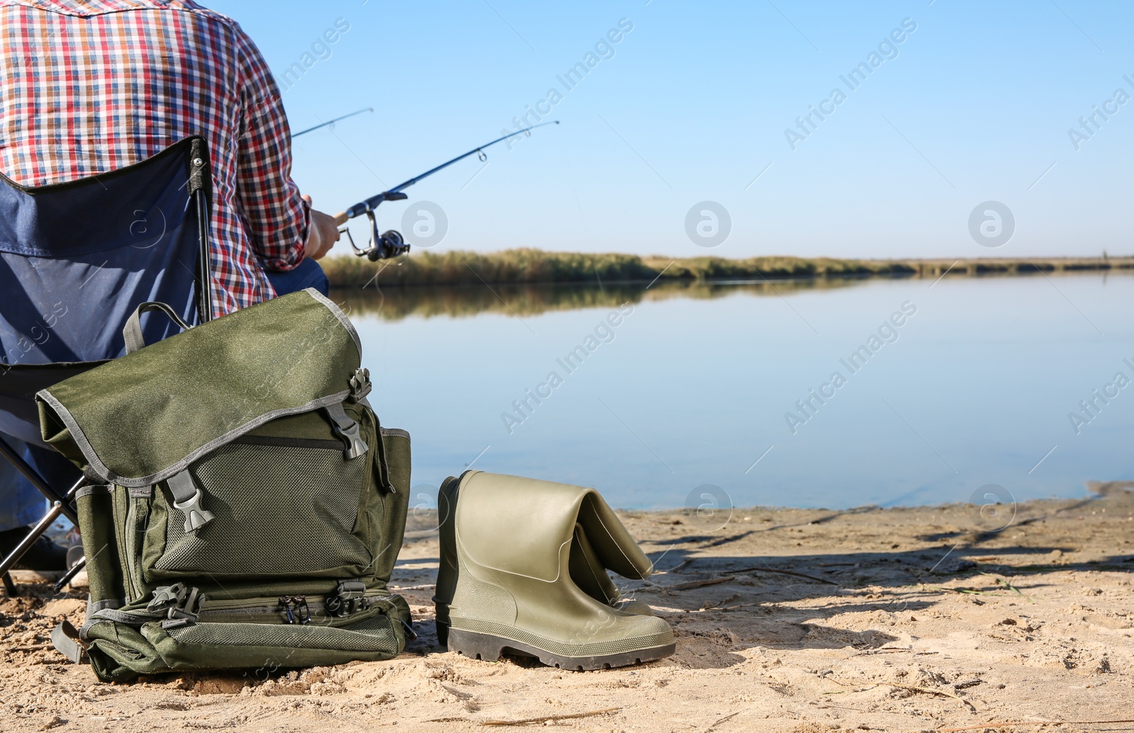 Photo of Man fishing at riverside on sunny day. Space for text