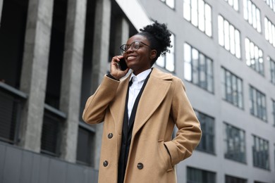 Photo of Happy woman talking on smartphone outdoors. Lawyer, businesswoman, accountant or manager