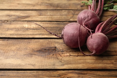 Photo of Raw ripe beets on wooden table. Space for text