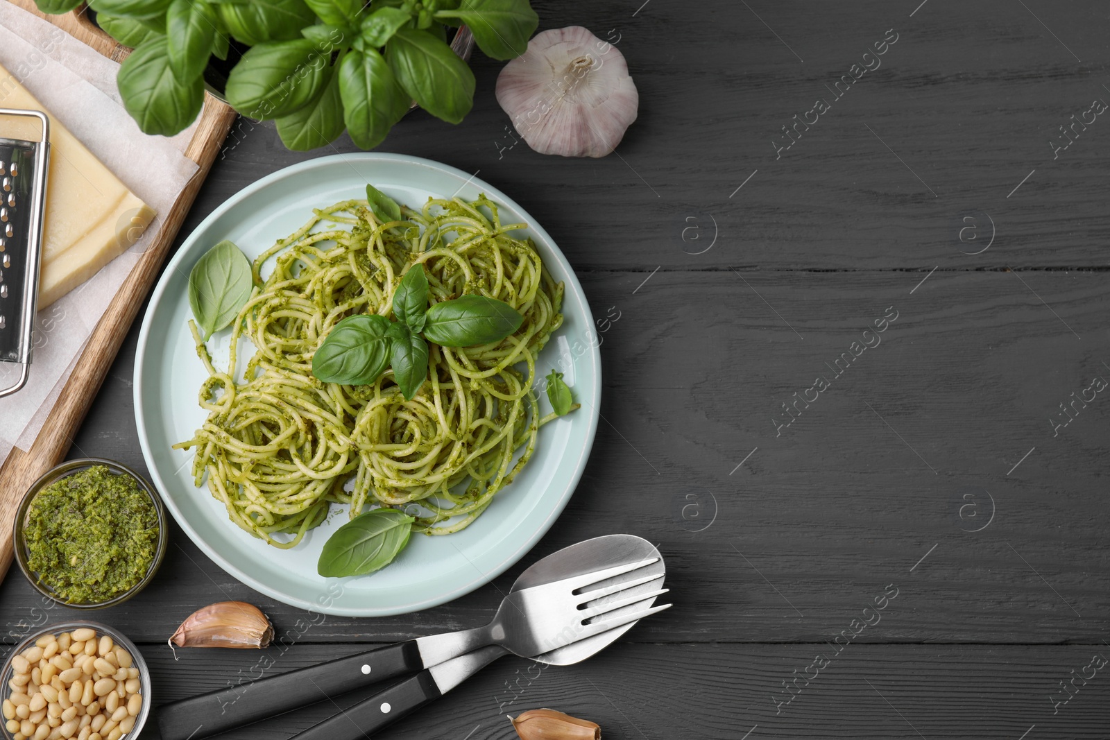 Photo of Delicious pasta with pesto sauce and basil served on grey wooden table, flat lay. Space for text
