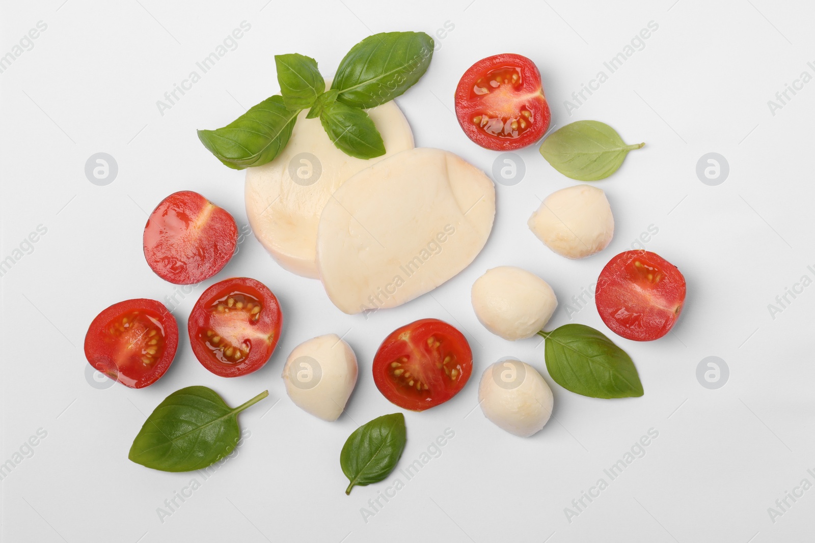 Photo of Mozzarella, tomatoes and basil on white background, flat lay. Caprese salad ingredients