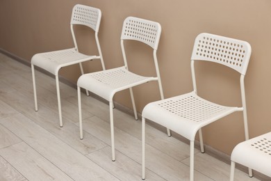 Photo of Many chairs near beige wall in waiting area indoors