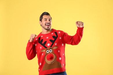 Photo of Portrait of happy young man in Christmas sweater on yellow background