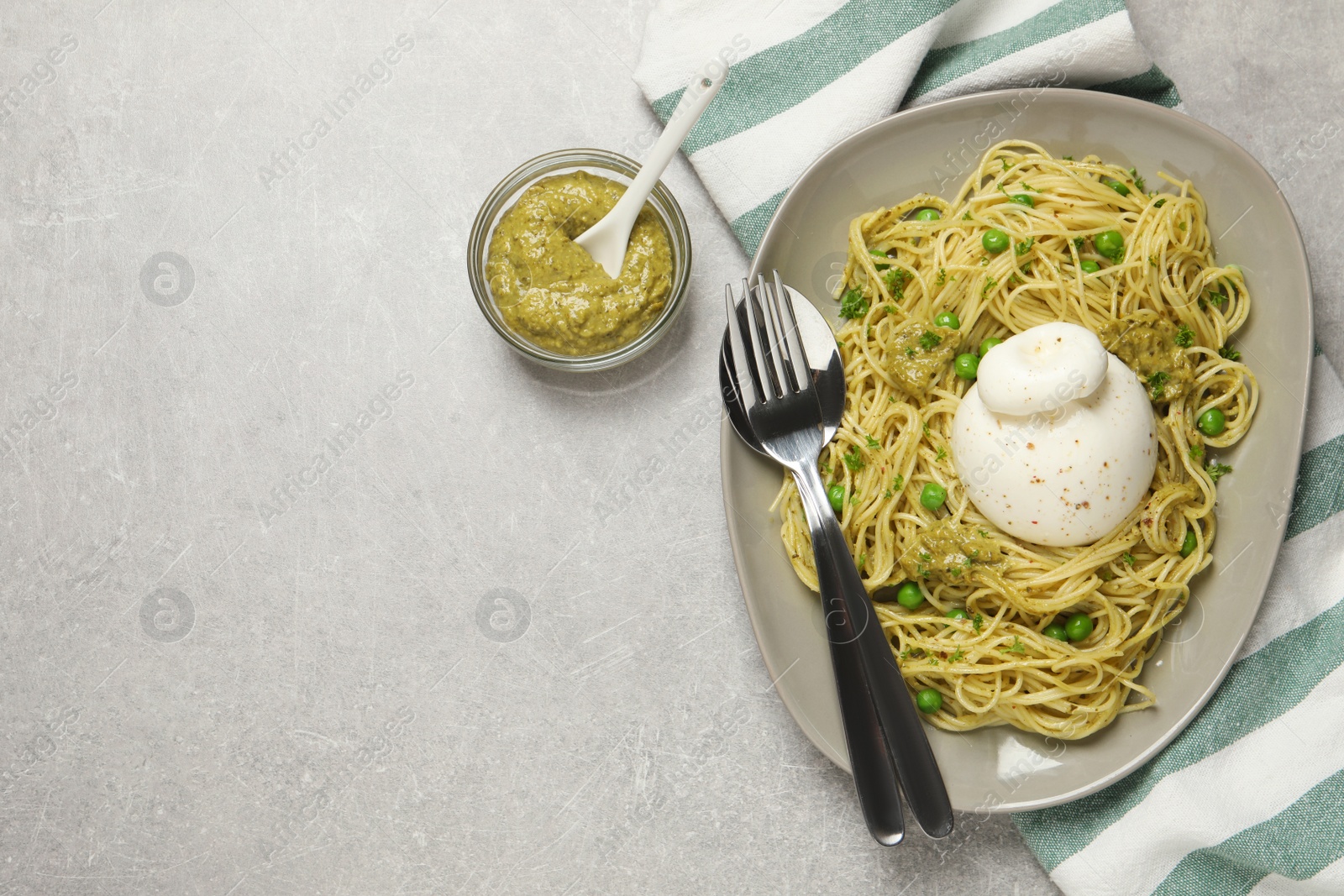 Photo of Delicious spaghetti with burrata cheese, peas and pesto sauce on light grey table, flat lay. Space for text