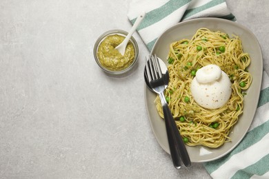 Delicious spaghetti with burrata cheese, peas and pesto sauce on light grey table, flat lay. Space for text