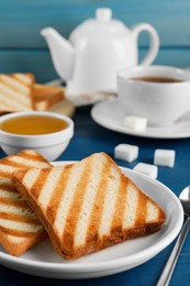 Slices of tasty toasted bread on blue wooden table, closeup