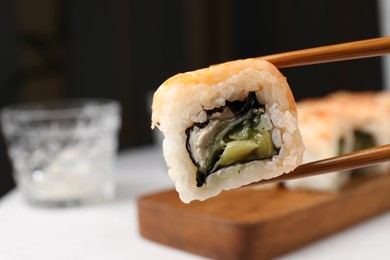 Photo of Holding delicious sushi roll with chopsticks, closeup. Space for text