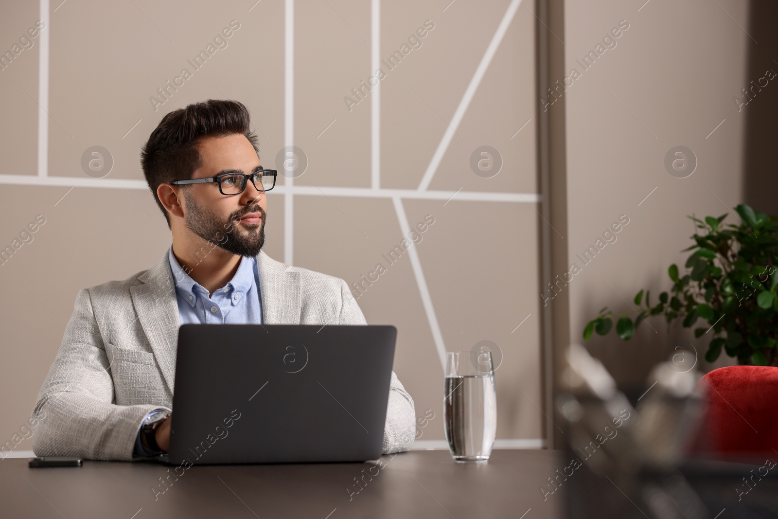 Photo of Happy young man with glasses working on laptop at table in office. Space for text