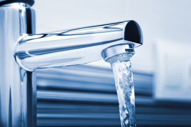 Image of Water flowing from tap on blurred background, closeup