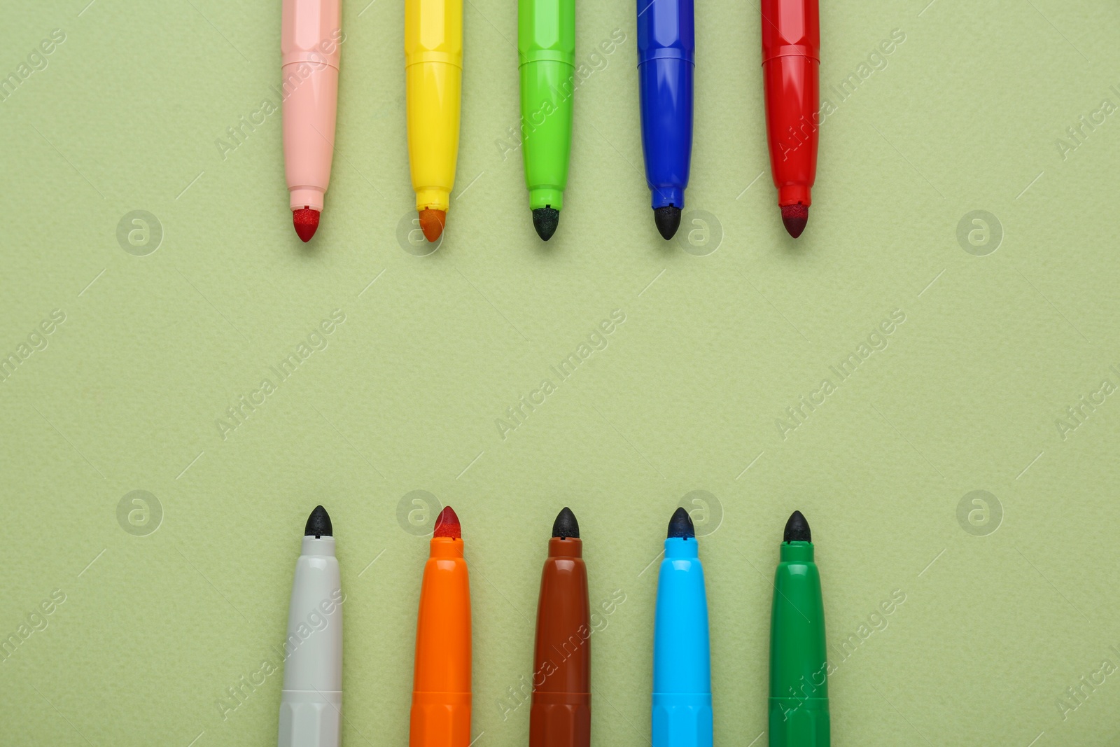 Photo of Different colorful markers on light green background, flat lay. Space for text