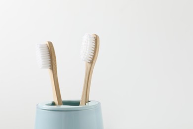 Photo of Bamboo toothbrushes in holder on white background, closeup. Space for text