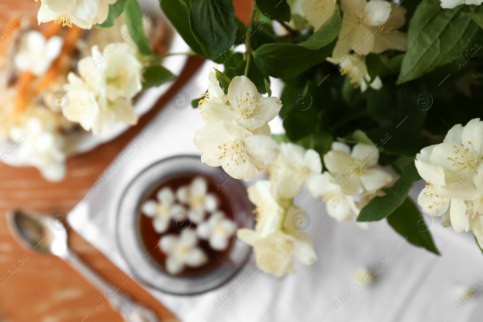 Photo of Branch of jasmine plant with beautiful white flowers on blurred background, top view. Space for text