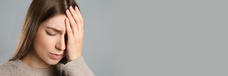 Image of Young woman suffering from migraine on grey background, space for text. Banner design