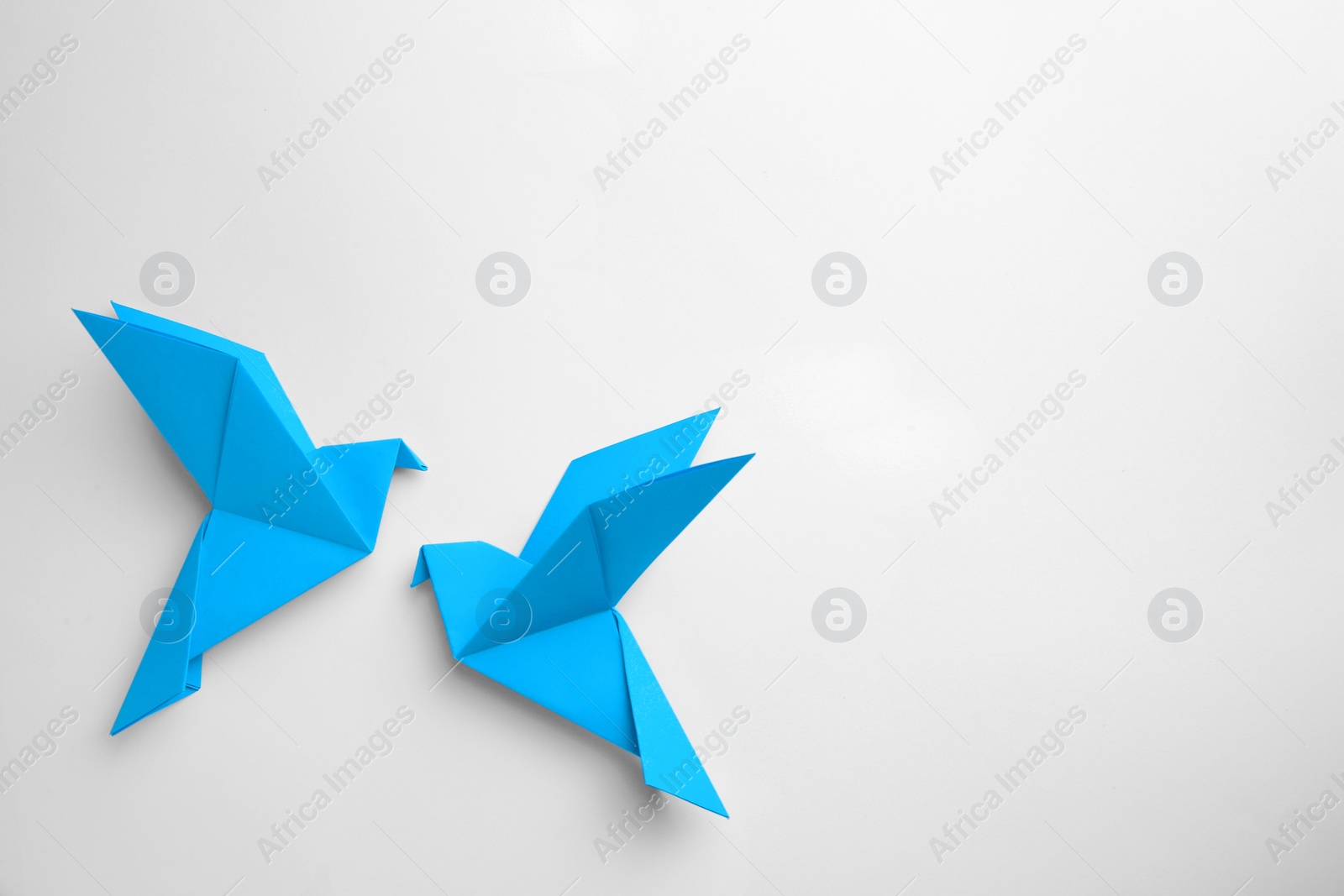 Photo of Origami art. Colorful handmade paper birds on white background, flat lay. Space for text