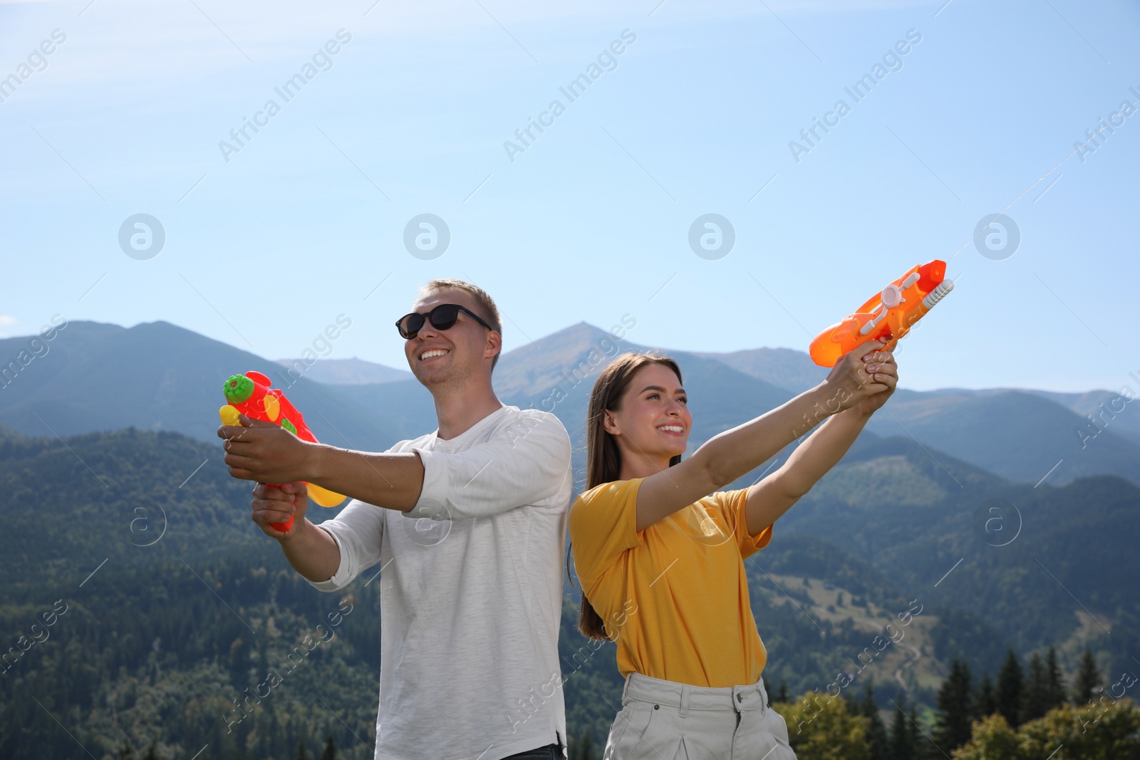 Photo of Happy couple with water guns having fun in mountains