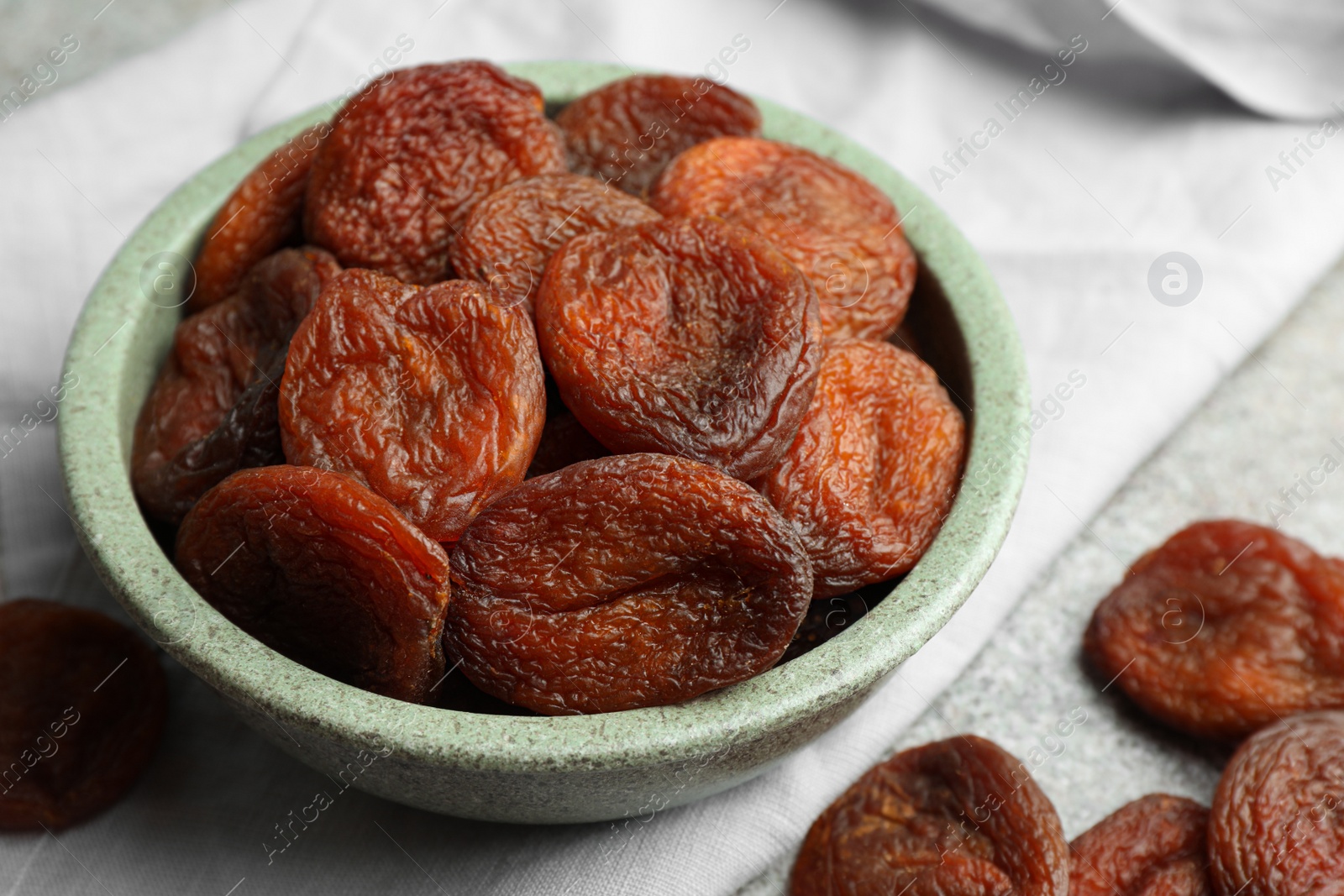 Photo of Bowl of tasty apricots on grey table, closeup. Dried fruits