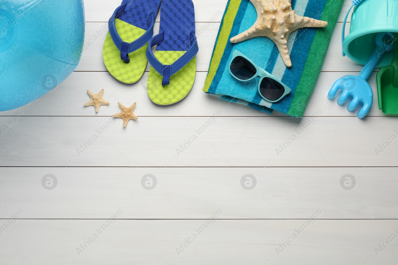 Photo of Flat lay composition with beach ball, plastic toys and accessories on white wooden background. Space for text