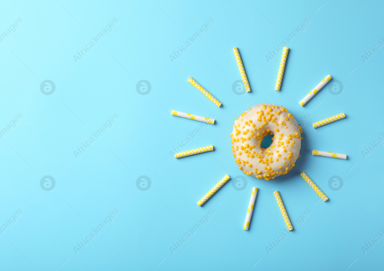 Photo of Sun made with donut and straws on light blue background, flat lay. Space for text