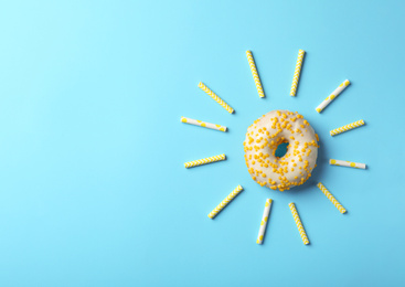 Photo of Sun made with donut and straws on light blue background, flat lay. Space for text