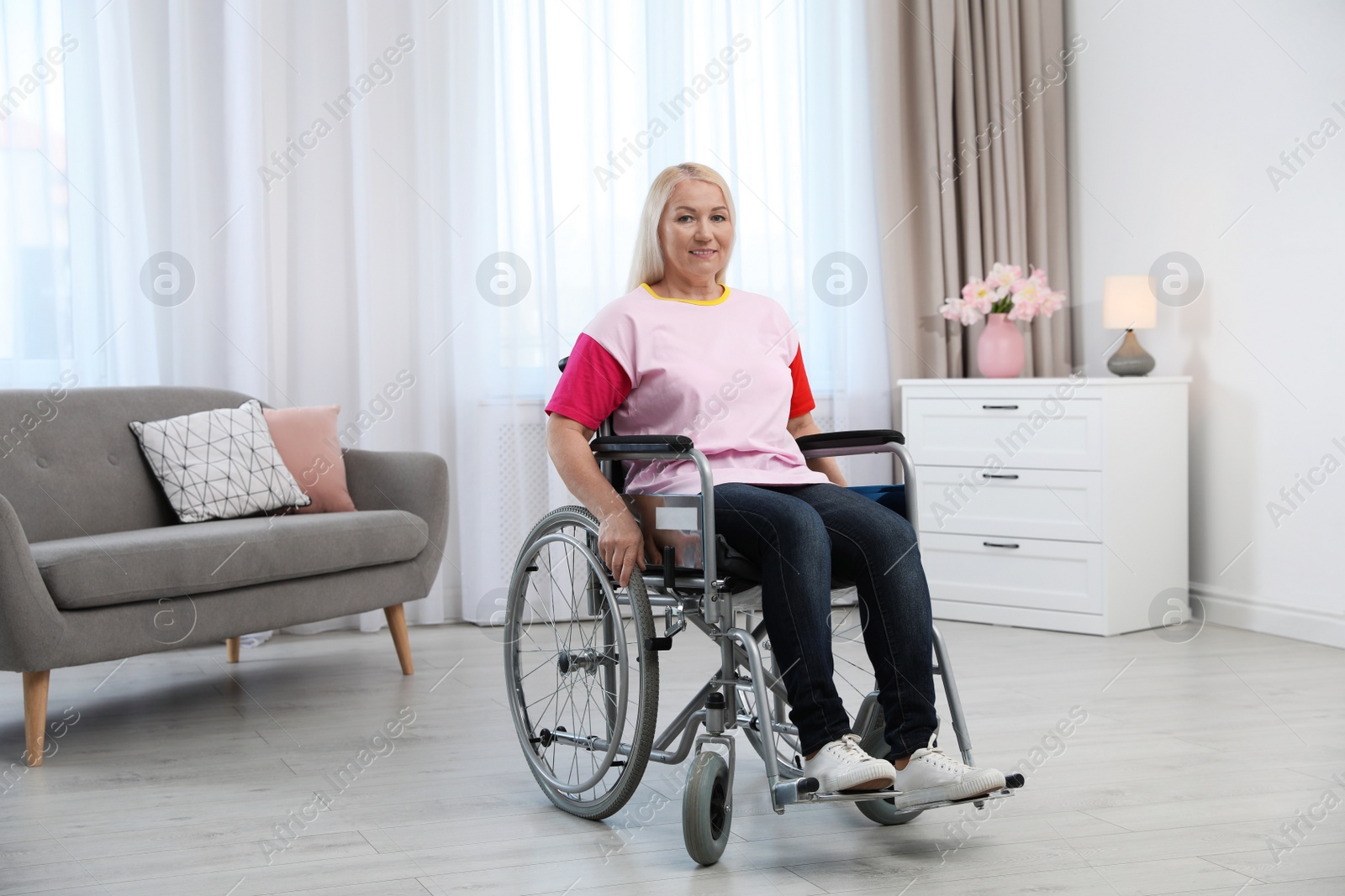 Photo of Mature woman sitting in wheelchair at home