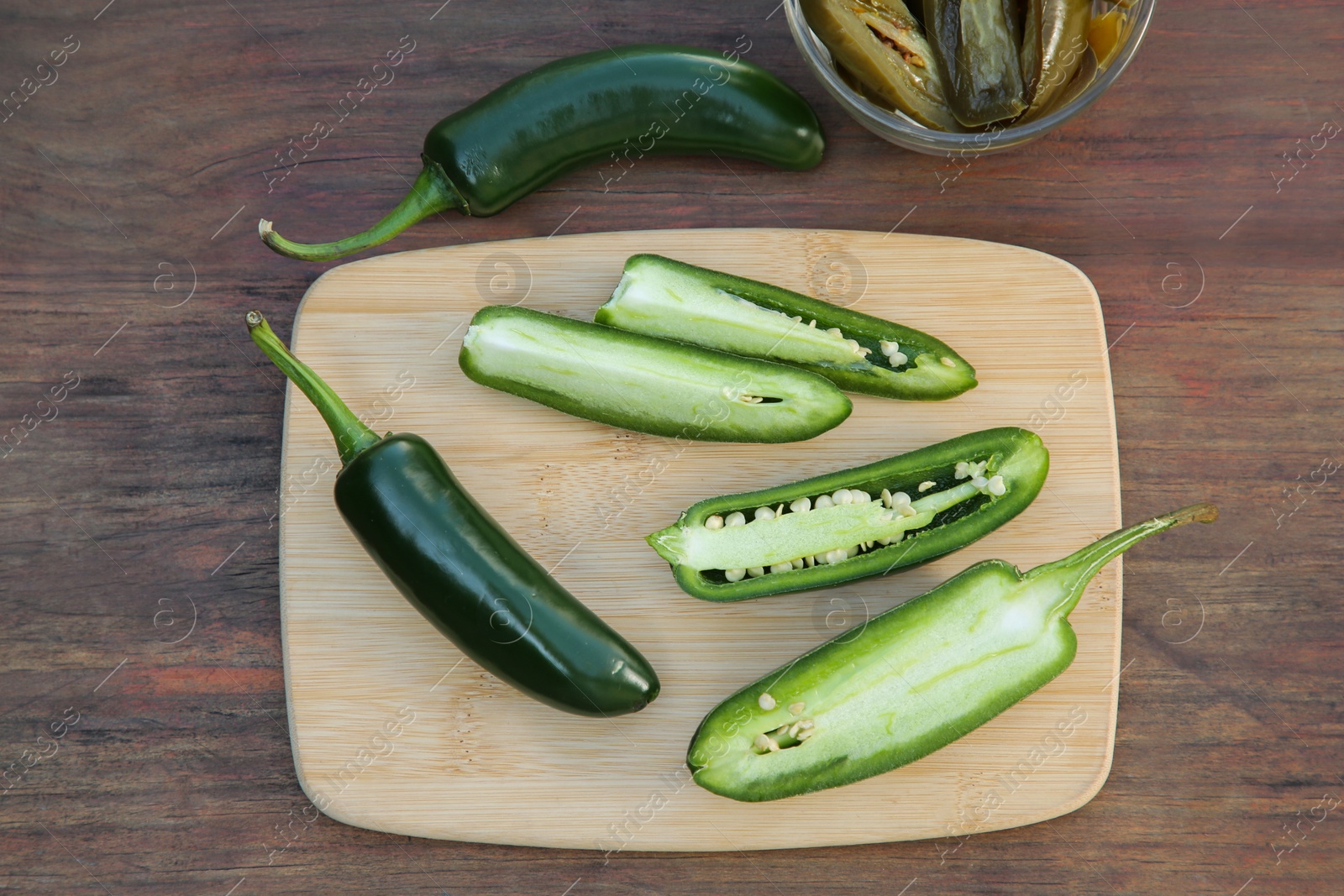 Photo of Fresh and pickled green jalapeno peppers on wooden table, flat lay