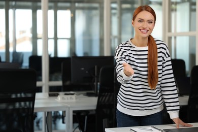 Photo of Happy woman welcoming and offering handshake in office, space for text